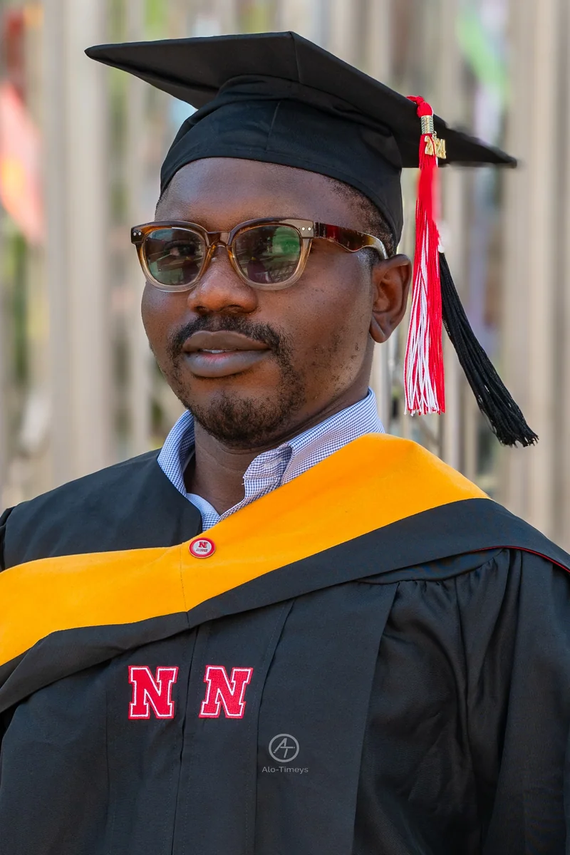 A graduate wears Nebraska regalia, a gold hood and a mortarboard with a red, white and black 2024 tassel.